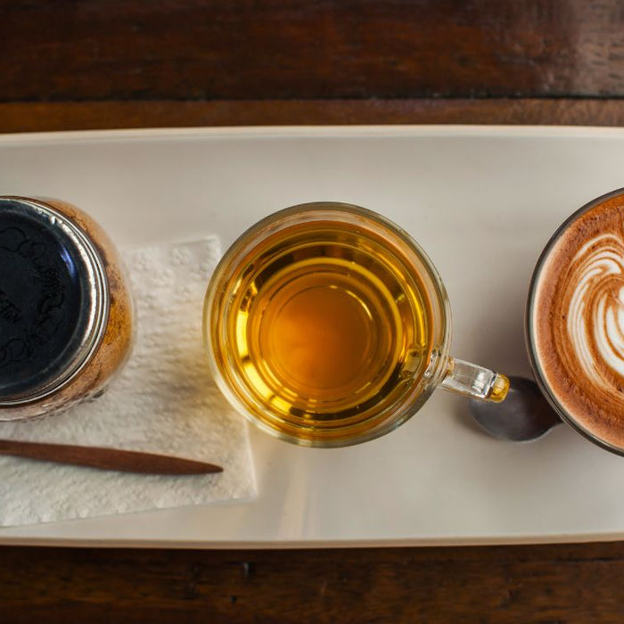 Black coffee, herbal tea, and latte side by side on a tray - can you drink coffee during a detox cleanse