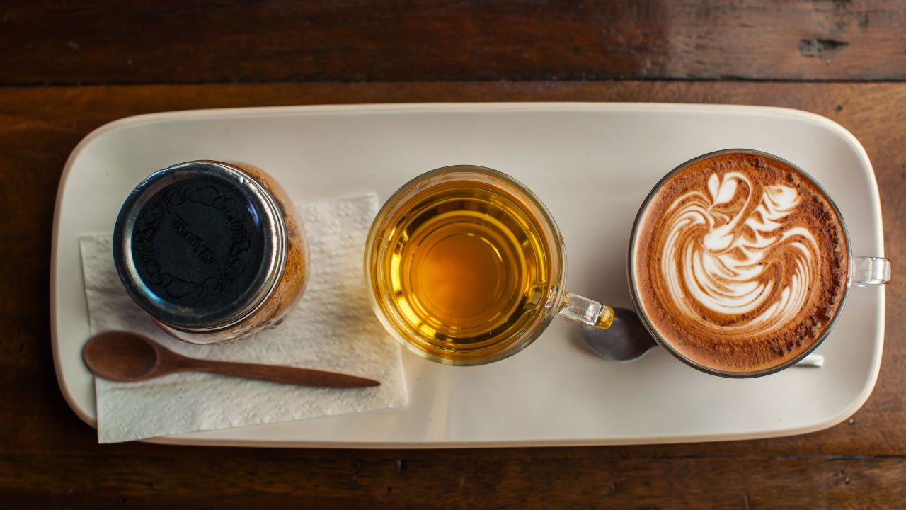 Black coffee, herbal tea, and latte side by side on a tray - can you drink coffee during a detox cleanse