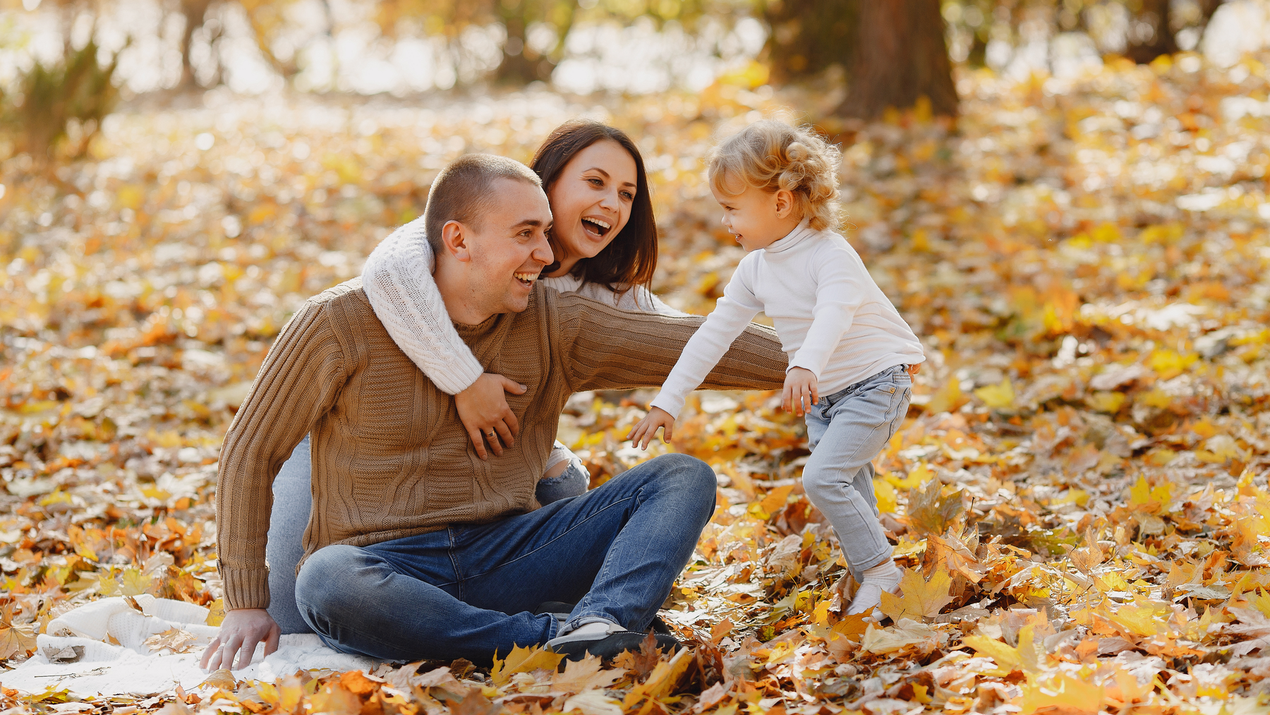 Happy family playing together in autumn leaves outdoors staying healthy through flu season