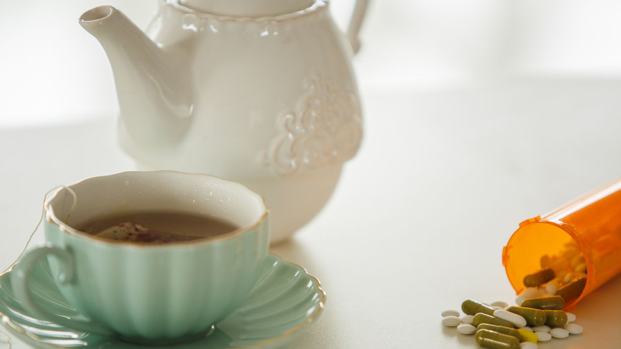 Herbal tea cup with teapot and prescription capsules - supporting liver wellness on long-term medications