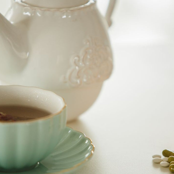 Herbal tea cup with teapot and prescription capsules - supporting liver wellness on long-term medications