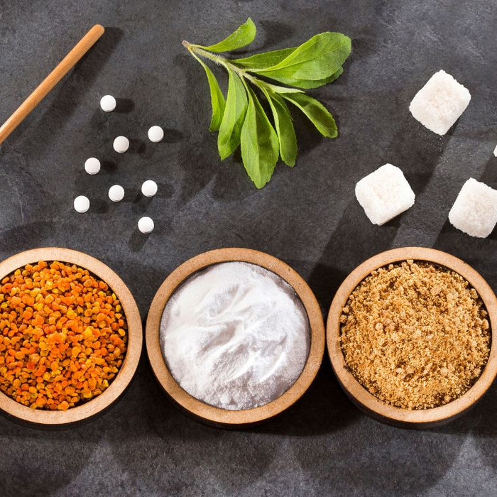 Natural sweeteners comparison including honey, bee pollen, stevia, brown sugar and white sugar in wooden bowls