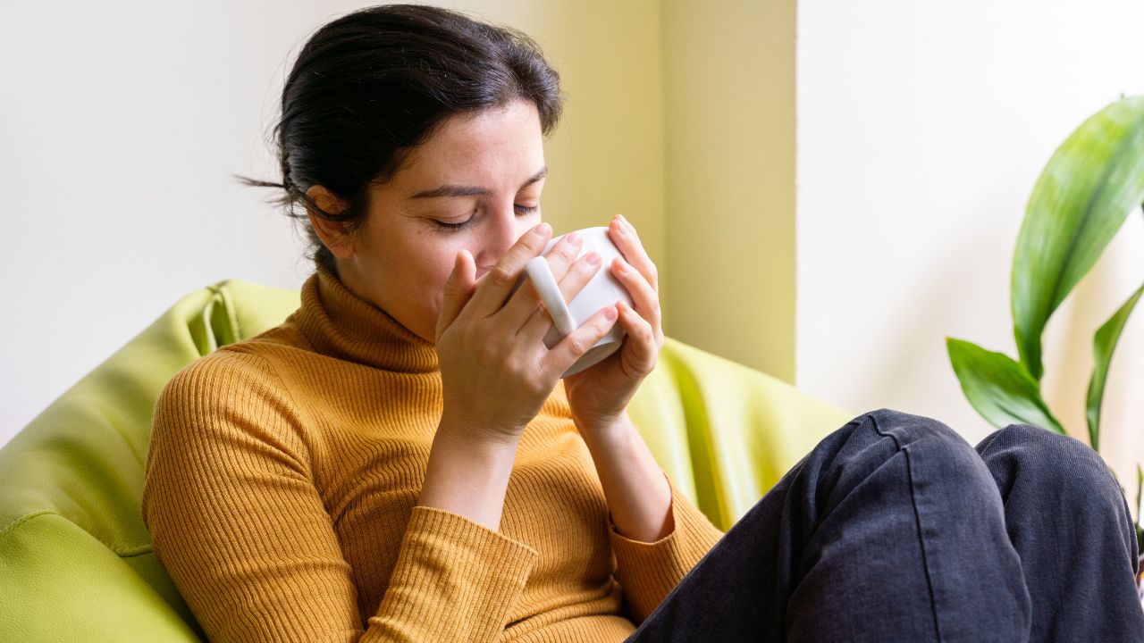 Woman drinking herbal tea at home - how to start a colon cleanse beginner guide by SpeedyVite
