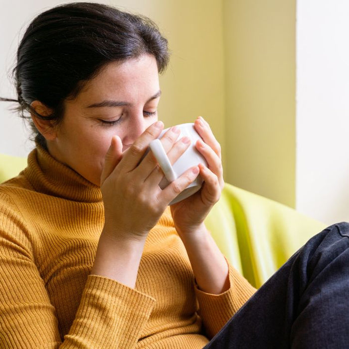 Woman drinking herbal tea at home - how to start a colon cleanse beginner guide by SpeedyVite