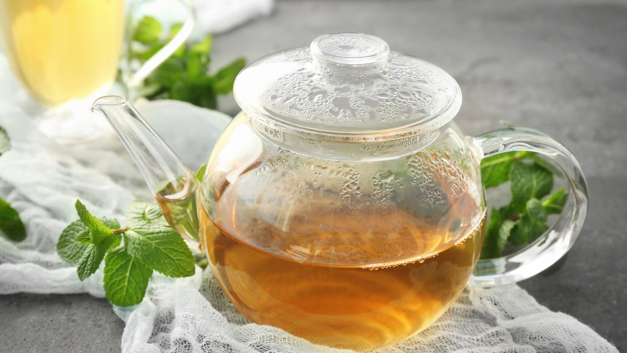 Glass teapot of herbal kidney cleanse tea with fresh mint leaves