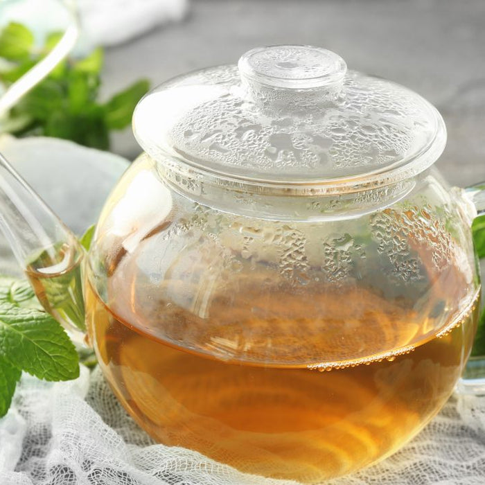 Glass teapot of herbal kidney cleanse tea with fresh mint leaves
