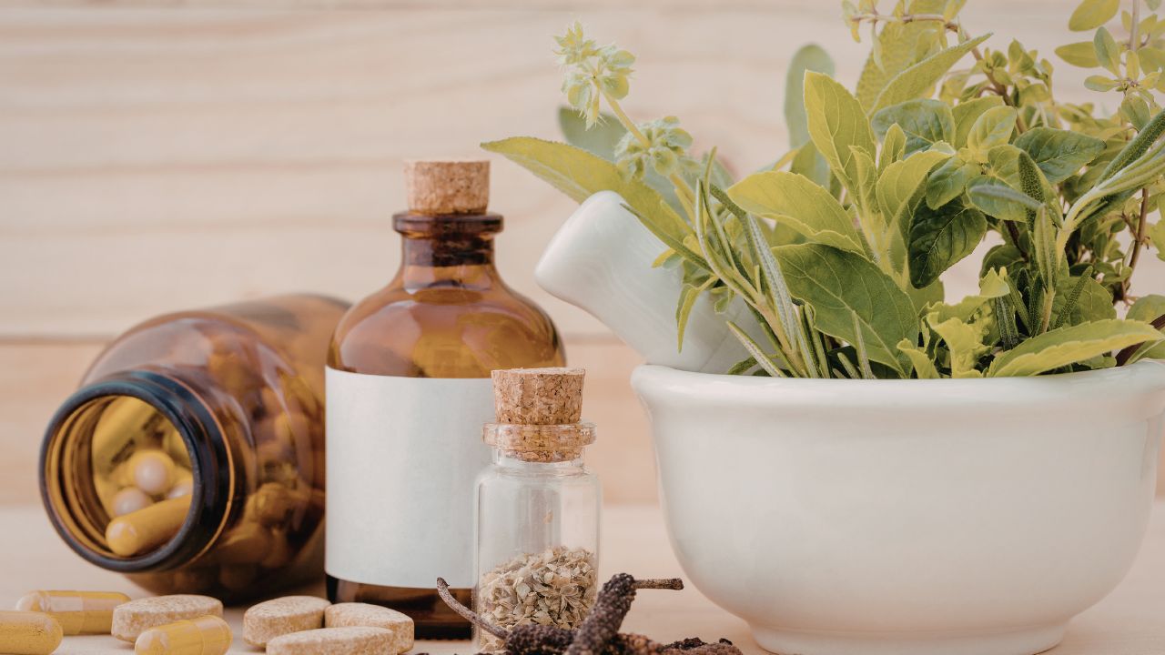 Herbal supplement capsules, tincture drops bottle, and dried herbs representing kidney cleanse tea, drops, and capsules formats