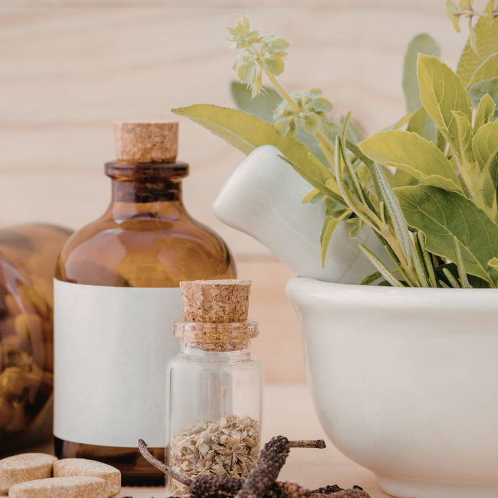 Herbal supplement capsules, tincture drops bottle, and dried herbs representing kidney cleanse tea, drops, and capsules formats