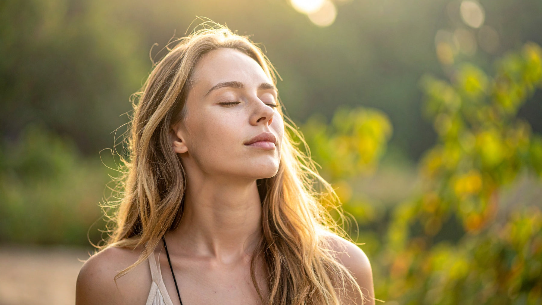 Woman with eyes closed enjoying natural sunlight and fresh air outdoors feeling healthy and well