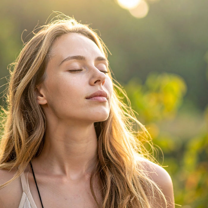 Woman with eyes closed enjoying natural sunlight and fresh air outdoors feeling healthy and well