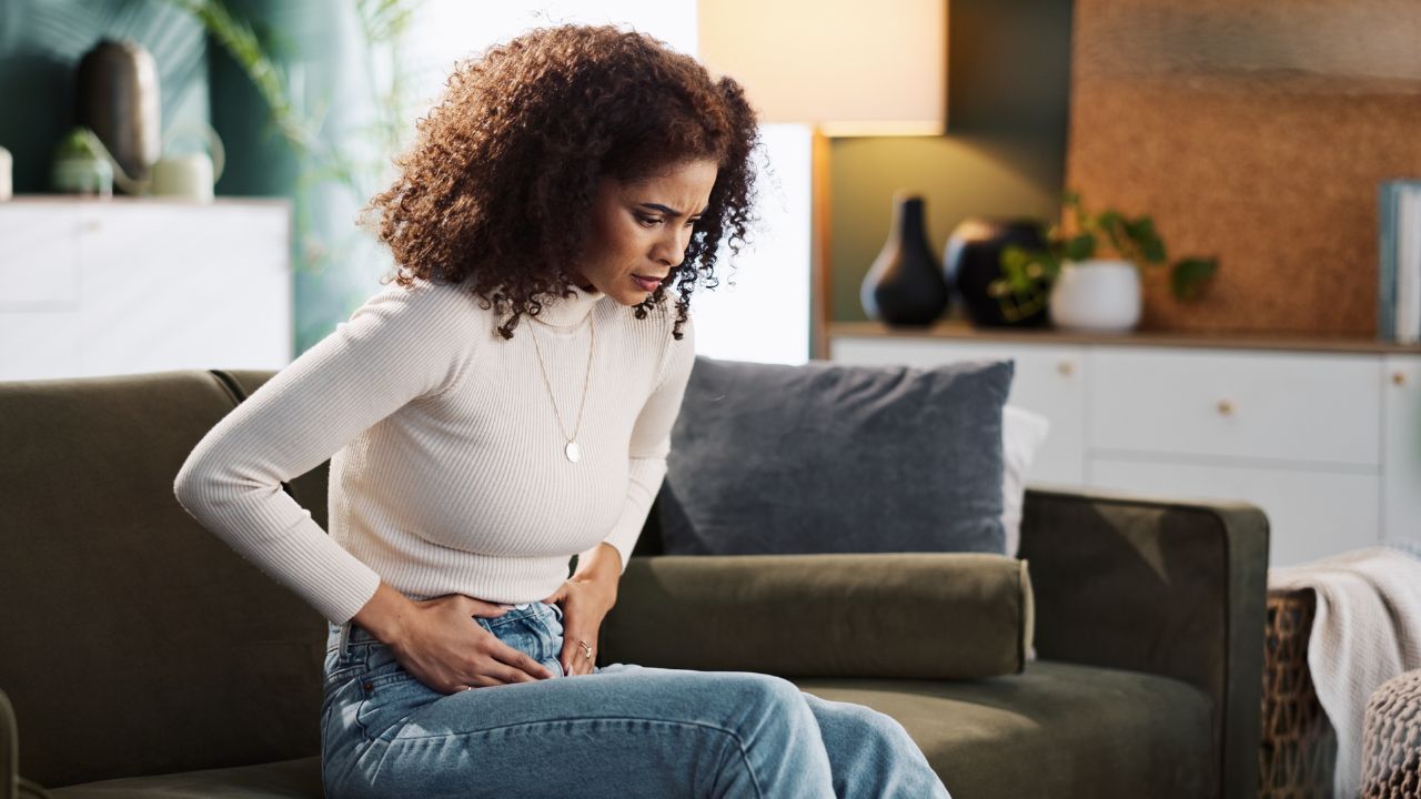 Woman holding stomach experiencing digestive discomfort - signs your colon may need herbal support