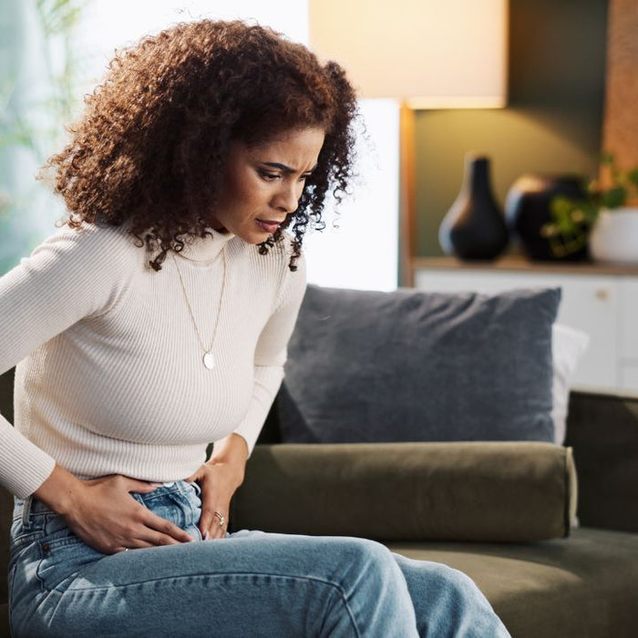 Woman holding stomach experiencing digestive discomfort - signs your colon may need herbal support